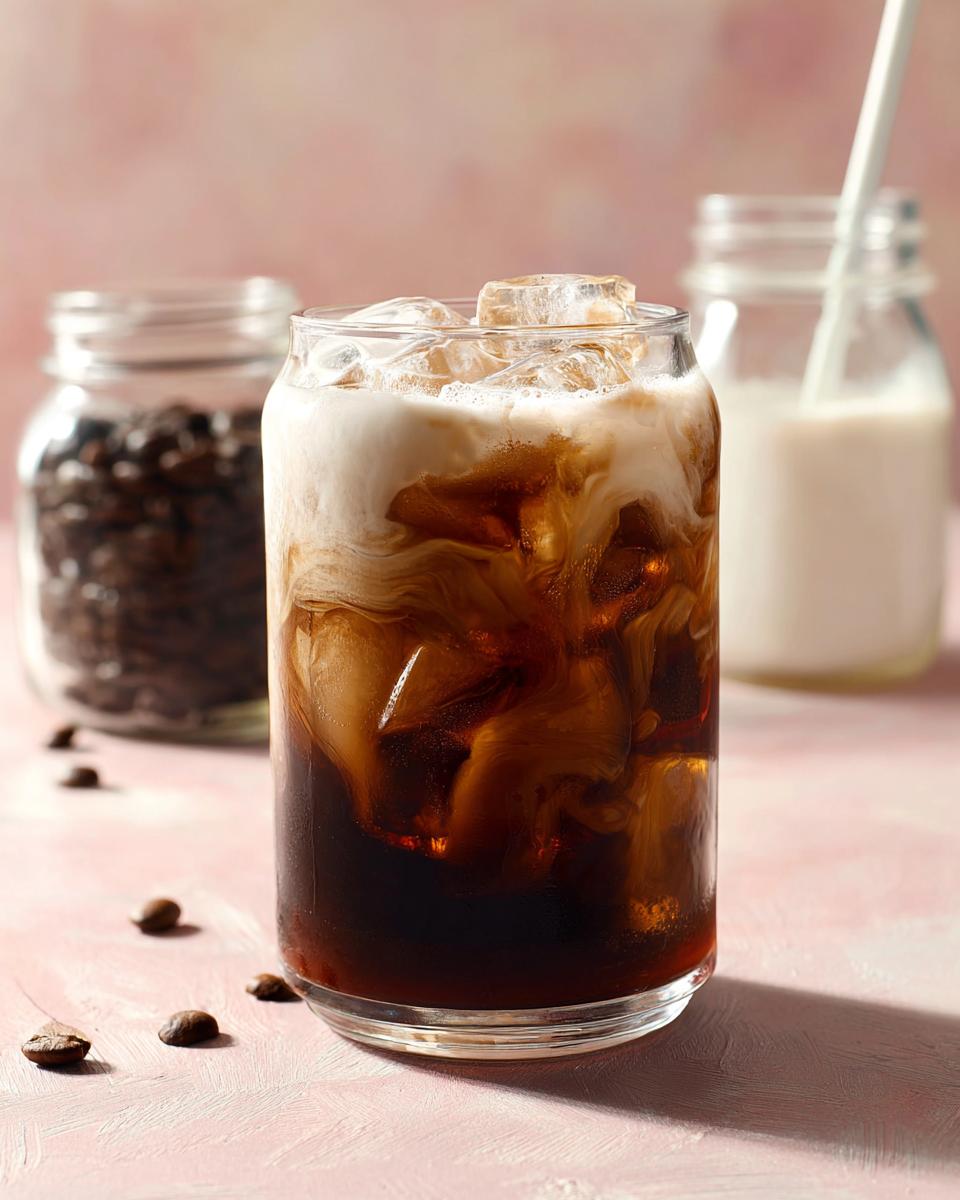 A refreshing glass of Cold Brew with Vanilla Sweet Cream, with ice cubes and swirls of cream.