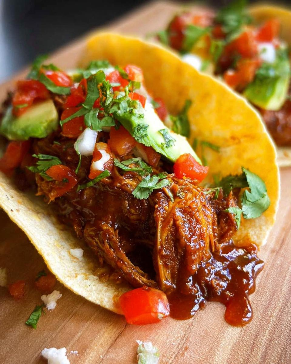 Close-up of a delicious easy chicken taco filled with shredded chicken, avocado, tomatoes, and cilantro.