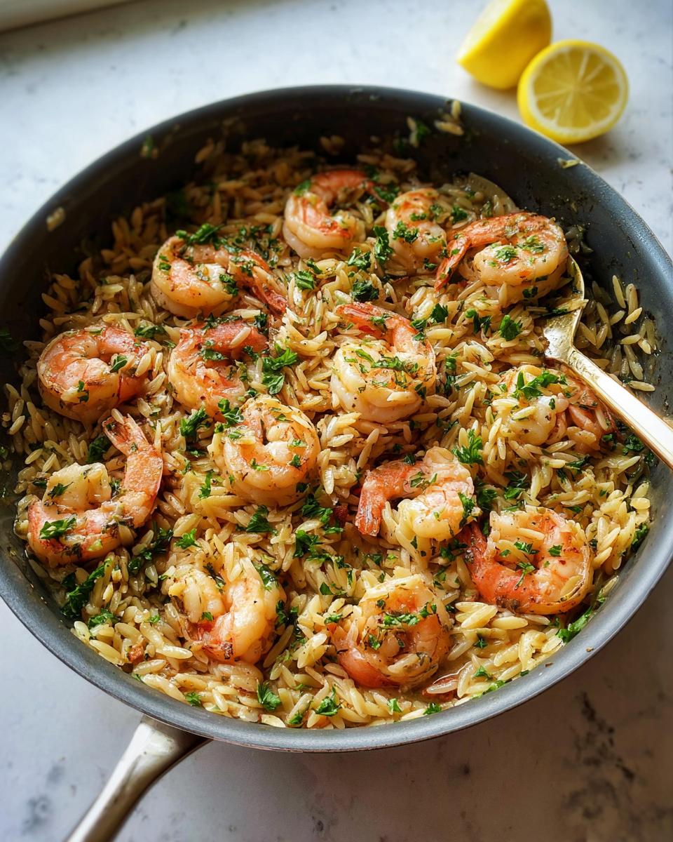 Overhead shot of Garlic‑Butter Shrimp & Orzo in a pan, garnished with parsley and lemon.