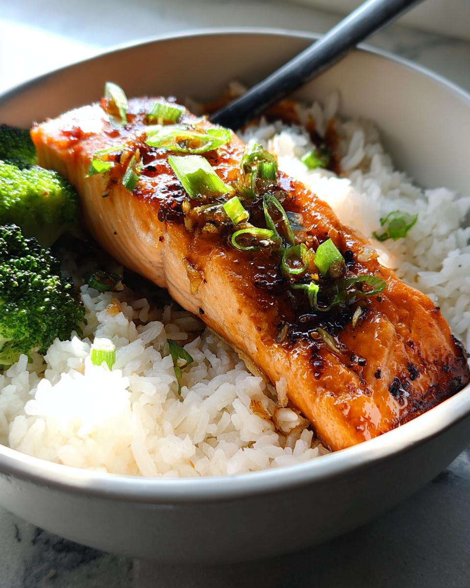 A delicious bowl of Honey-Garlic Salmon with Rice, topped with green onions and served with broccoli.