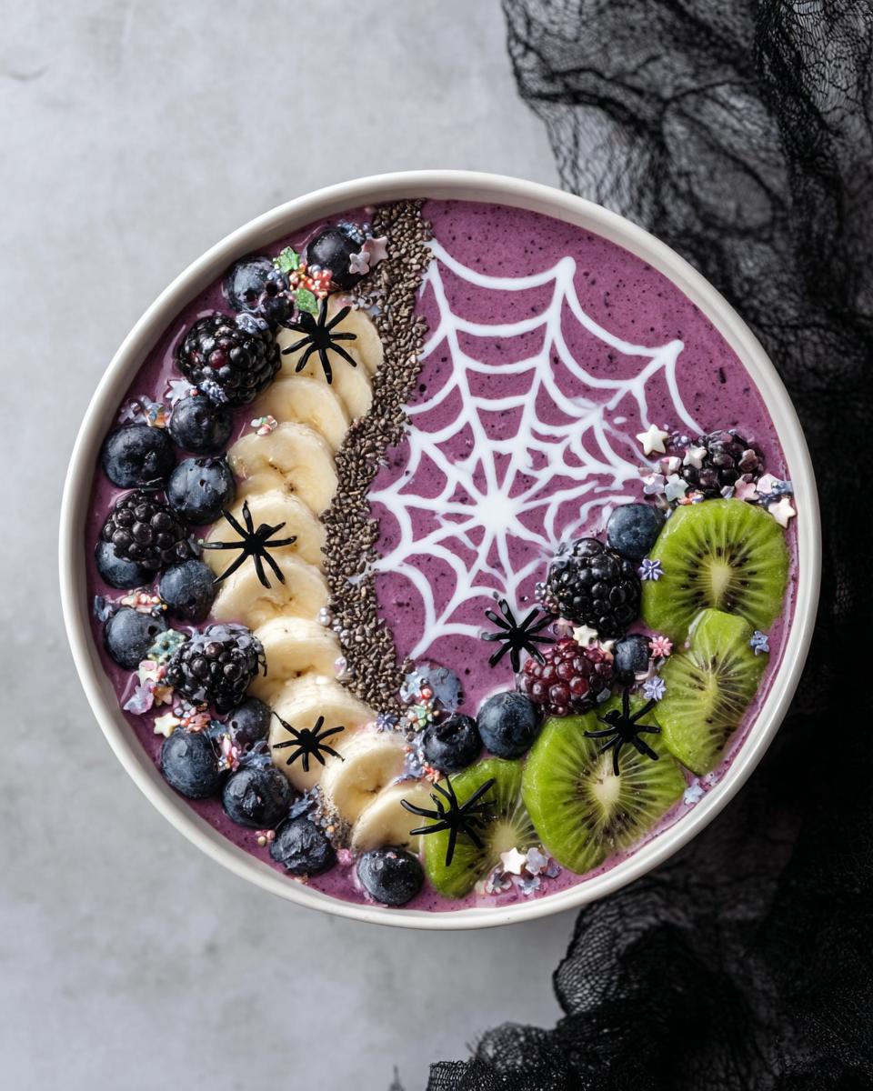 A vibrant purple Spooky Halloween Smoothie Bowl decorated with a white spiderweb, fruits, and edible spiders.