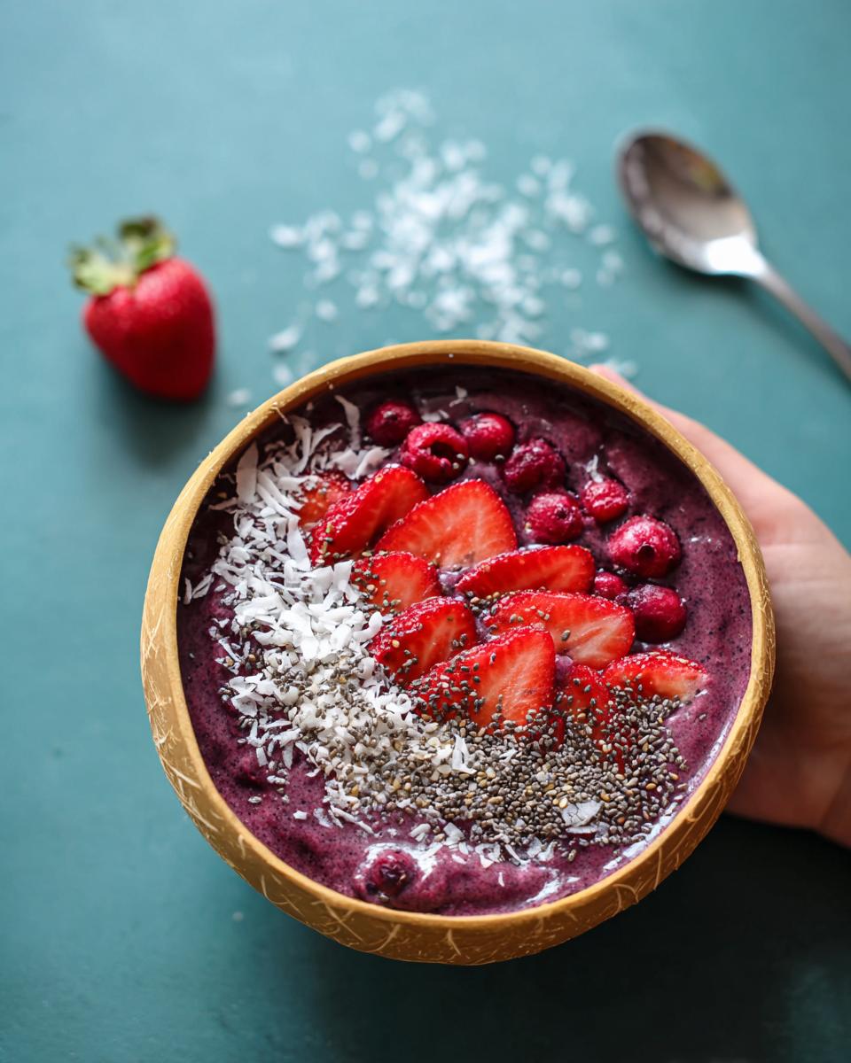 Overhead shot of a vibrant Spooky Smoothie Bowl topped with strawberries, raspberries, coconut, and chia seeds.