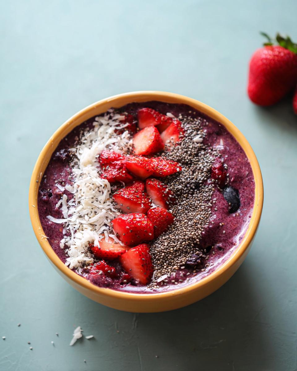 Overhead shot of a Spooky Smoothie Bowl topped with strawberries, coconut flakes, and chia seeds.