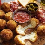 Cheesy, melted arancini balls served on a platter as part of an elegant New Year’s Eve Dinner Menu.
