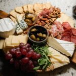 A fully assembled Cheese Board in 10 Minutes featuring various cheeses, cured meats, nuts, grapes, olives, and crackers.