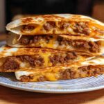A stack of four golden-brown quesadilla wedges filled with seasoned ground beef and melted cheese, showcasing Cheesy Beef Quesadillas.