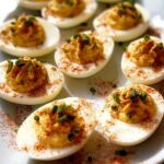 A platter of freshly made Classic Deviled Eggs, garnished with paprika and chopped chives.