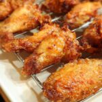 Close-up of golden brown, crispy baked chicken wings resting on a wire cooling rack.