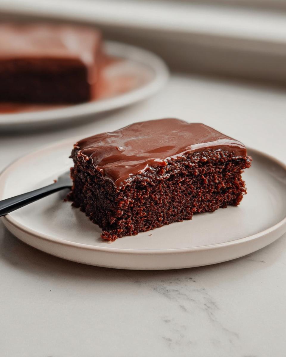 A square slice of rich, dark chocolate Easy Snacking Sheet Cake topped with glossy chocolate frosting.