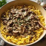 Rich Ground Beef Stroganoff with mushrooms and creamy sauce served over wide egg noodles in a skillet.
