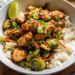 A vibrant bowl featuring glazed chicken pieces, roasted Brussels sprouts, and shredded carrots over white rice, a great example of 15 Healthy Dinner Ideas.
