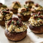 Close-up of freshly baked Stuffed Mushrooms (Make Ahead) topped with creamy filling and toasted pecans.