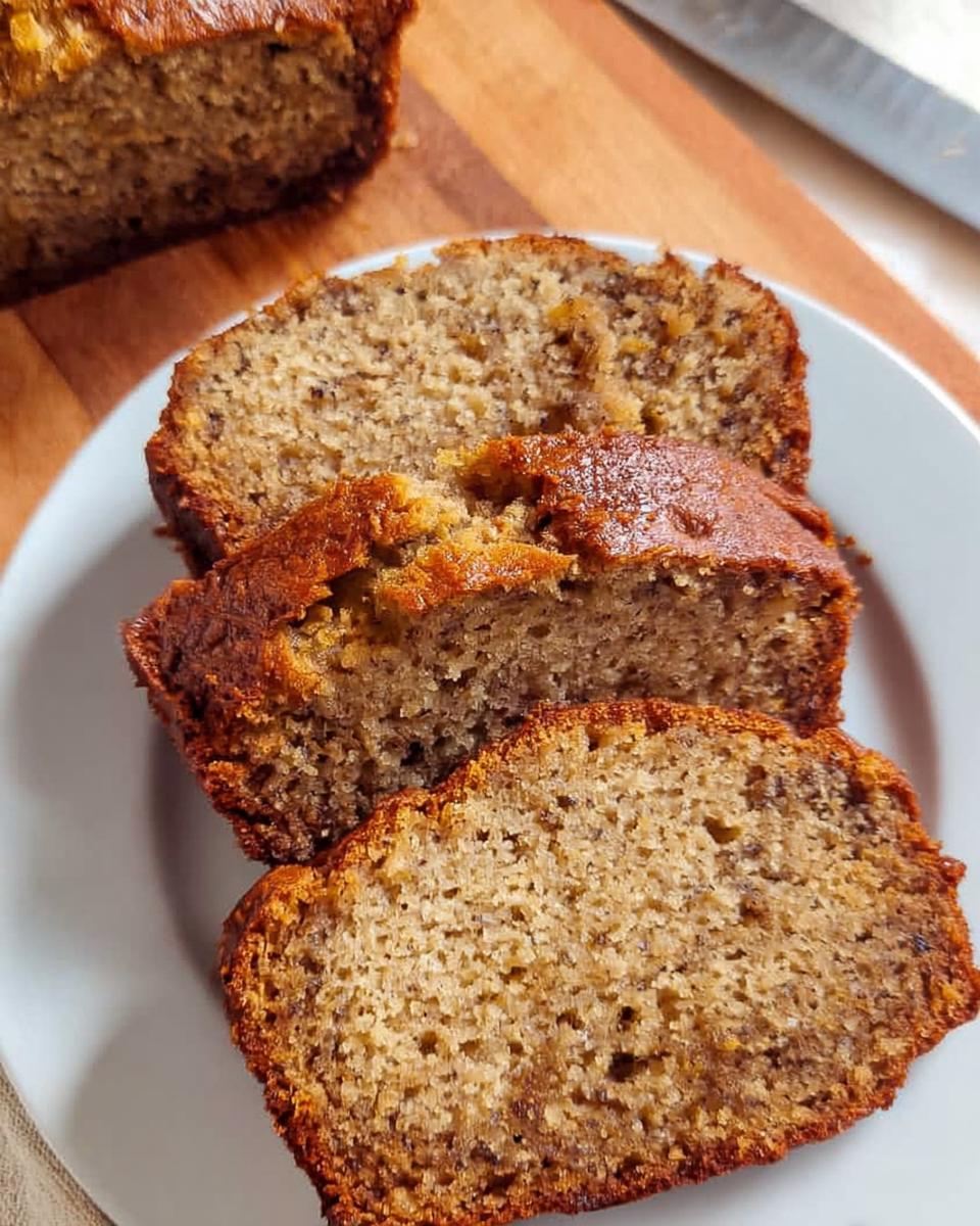 Three thick slices of moist One Bowl Banana Bread served on a white plate.
