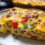 Close-up of a serving of Quick Breakfast Casserole showing eggs, cheese, bacon, and peppers.