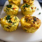 Close-up of freshly baked Breakfast Meal Prep Egg Cups garnished with parsley on a white cutting board.