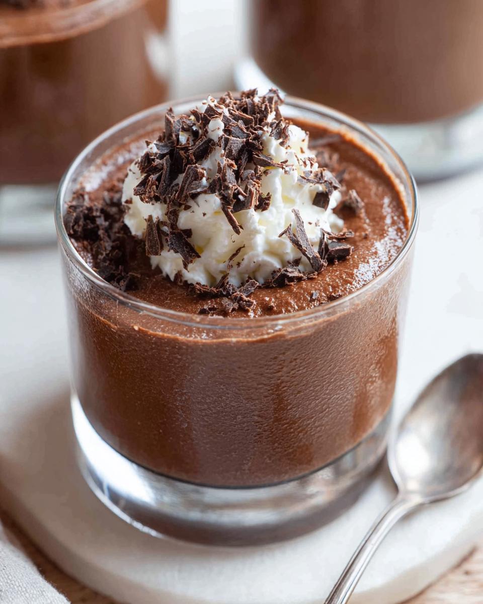 Close-up of a serving of rich Chocolate Mousse topped with whipped cream and chocolate shavings.