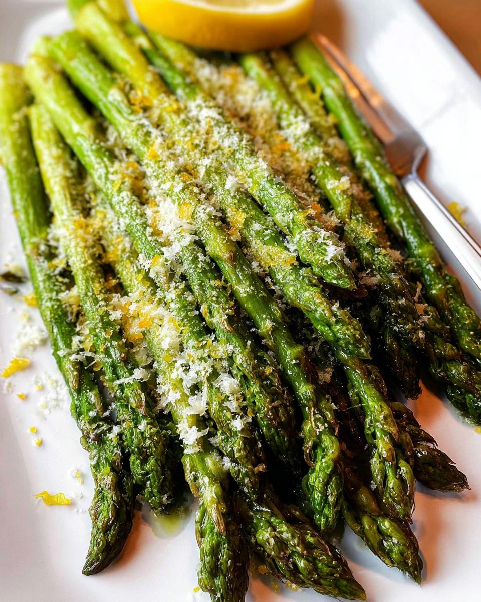 Close-up of bright green Roasted Asparagus with Parmesan cheese and lemon zest served on a white plate.