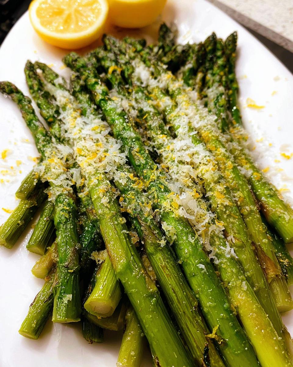 Close-up of bright green Roasted Asparagus with Parmesan cheese and lemon zest served on a white platter.