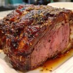 Close-up of a perfectly cooked Small Prime Rib Roast, showing a dark, herbed crust and a medium-rare pink center.