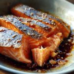 Close-up of three moist pieces of Soy Ginger Salmon glazed with sauce and topped with sesame seeds.