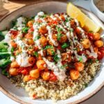 Close-up of a vibrant bowl featuring Spicy Chickpea Bowls served over quinoa, topped with sauce and fresh cucumber.