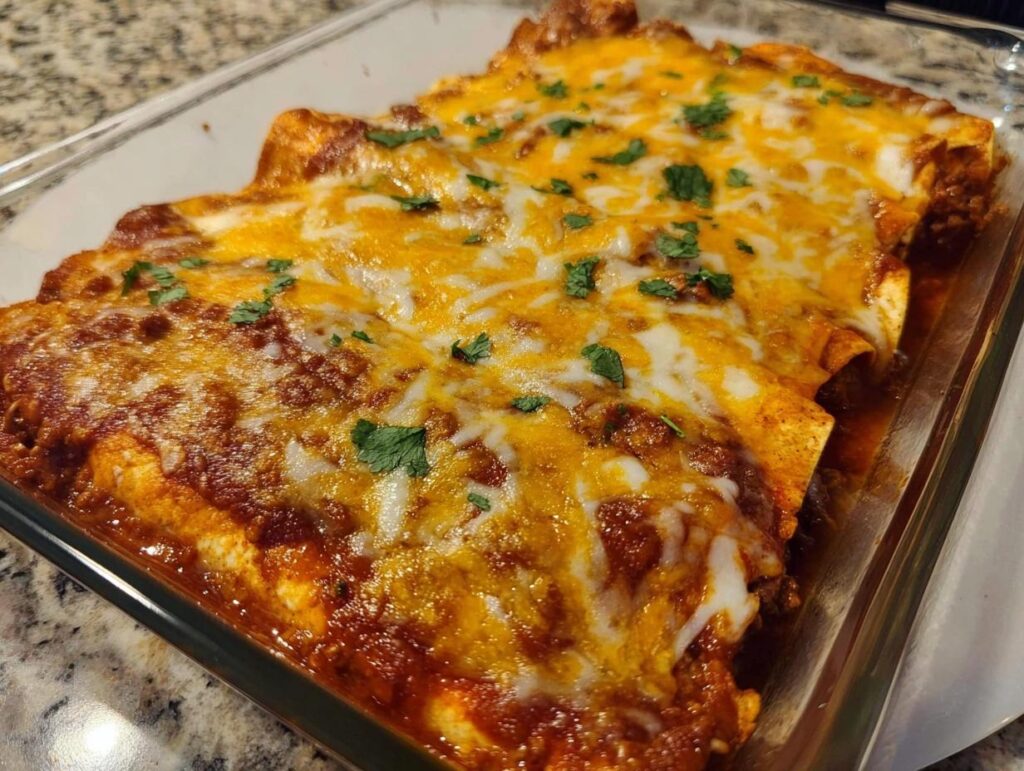 Close-up of freshly Baked Cheesy Beef Enchiladas covered in melted cheddar and Monterey Jack cheese and cilantro.