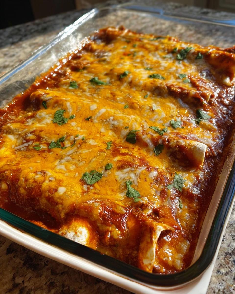 A close-up of freshly Baked Cheesy Beef Enchiladas covered in melted orange and white cheese and cilantro.