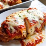 Close-up of a serving of Baked Chicken Parmesan with Mozzarella, cut open to show the white chicken breast inside, covered in marinara sauce and melted cheese.