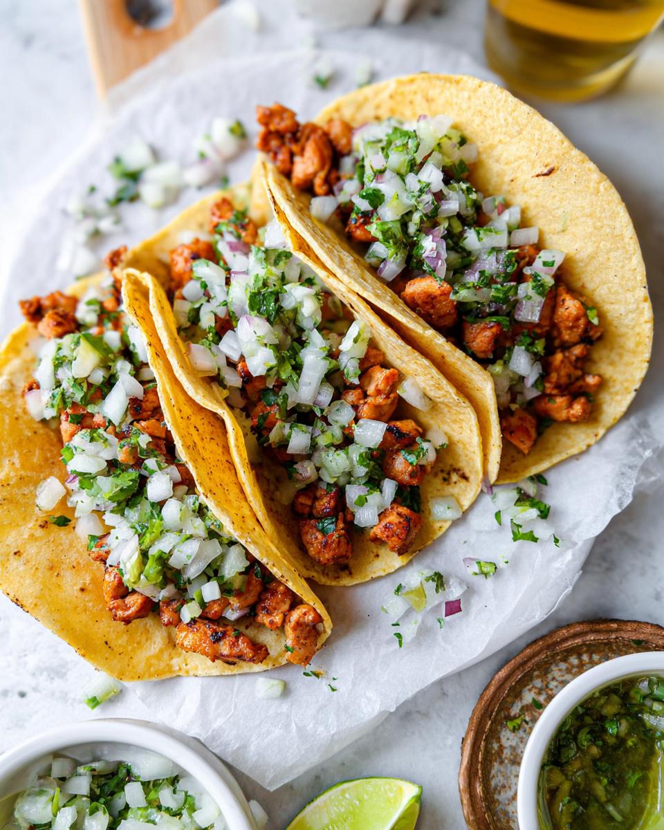 Three delicious Chicken Street Tacos served on corn tortillas, topped generously with diced white onion and cilantro.