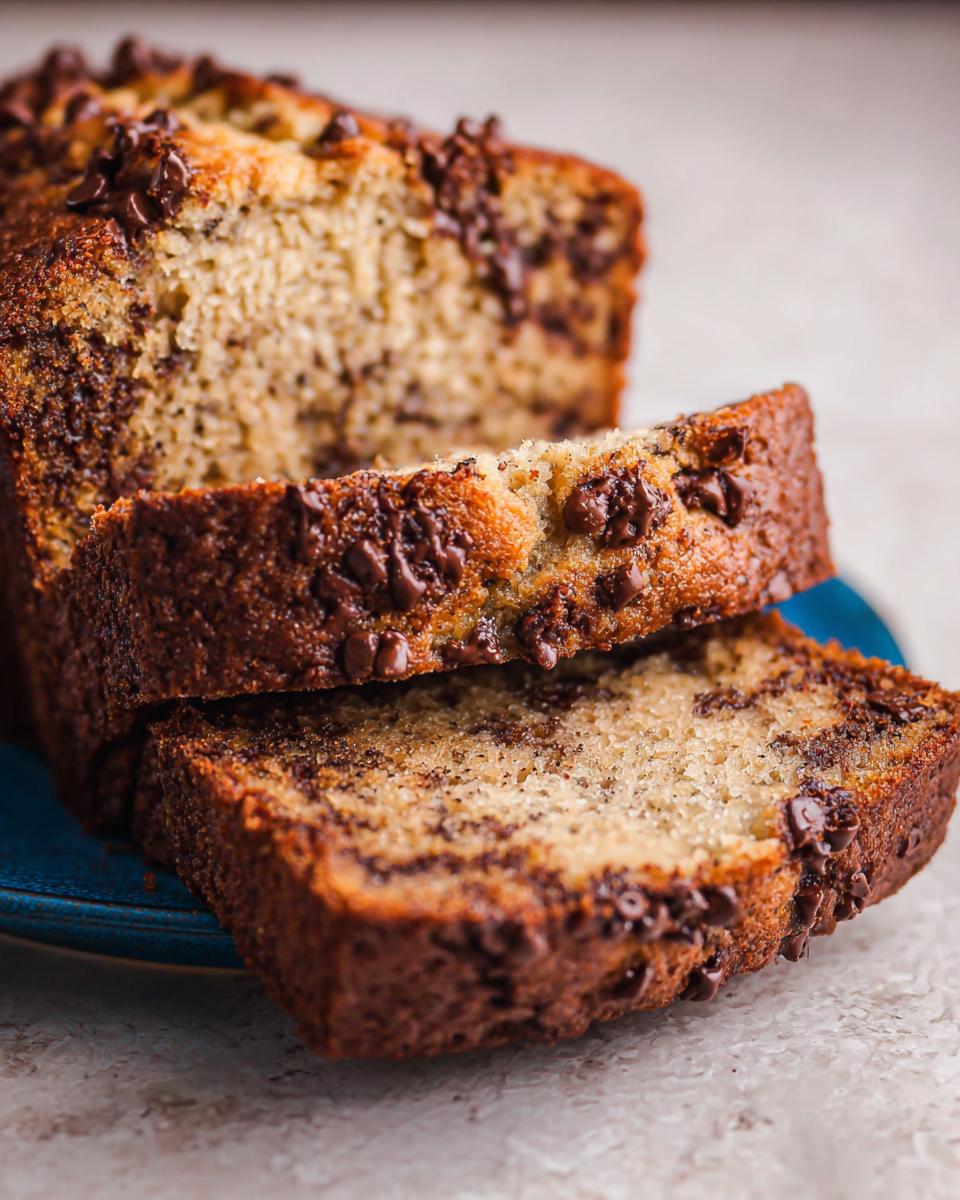 Close-up of a moist Chocolate Chip Banana Bread Loaf, with two thick slices resting against the main loaf.
