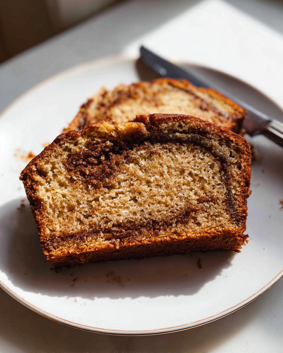 Close-up of a thick slice of Cinnamon Swirl Banana Bread showing the moist texture and dark cinnamon swirl.
