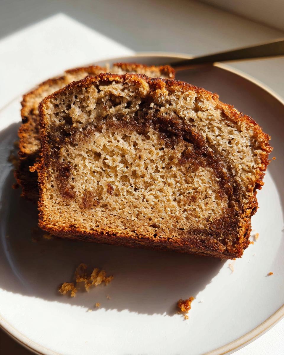 Close-up of a moist slice of Cinnamon Swirl Banana Bread showing the rich brown swirl texture.