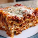 Close-up of a thick, layered slice of Classic Meat and Cheese Baked Lasagna with melted cheese topping.