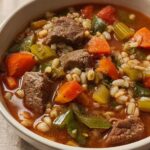 Close-up of a bowl filled with Hearty Beef and Vegetable Barley Soup, showing chunks of beef, carrots, celery, and barley.