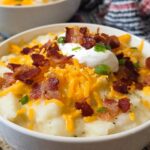 A close-up of creamy Loaded Baked Potato Soup with Bacon and Cheese, topped with shredded cheddar, bacon bits, sour cream, and chives.