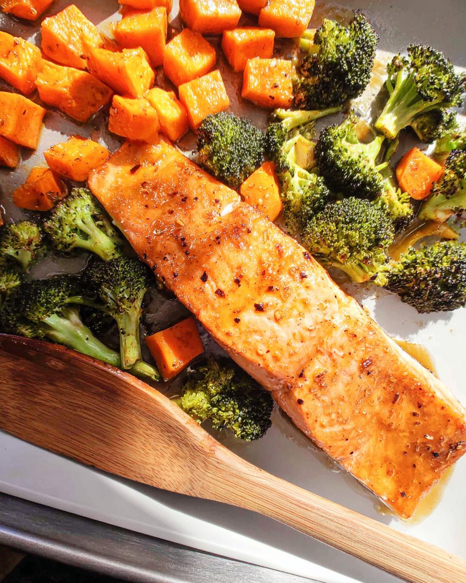 A glistening fillet of Maple Dijon Salmon Sheet Pan Dinner served with roasted broccoli florets and sweet potatoes.