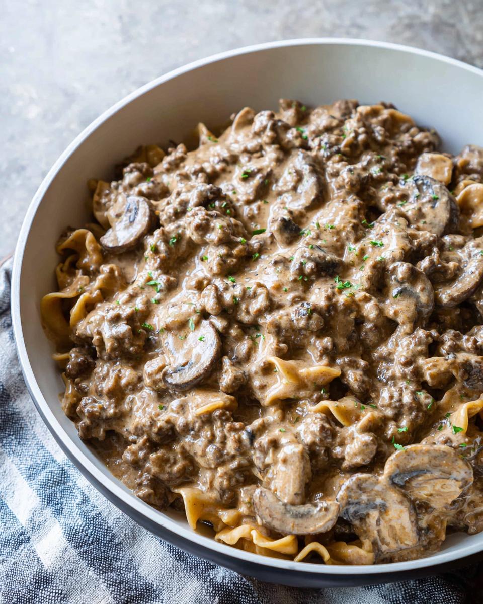 Close-up of a bowl filled with creamy One Pot Ground Beef Stroganoff mixed with egg noodles and sliced mushrooms.