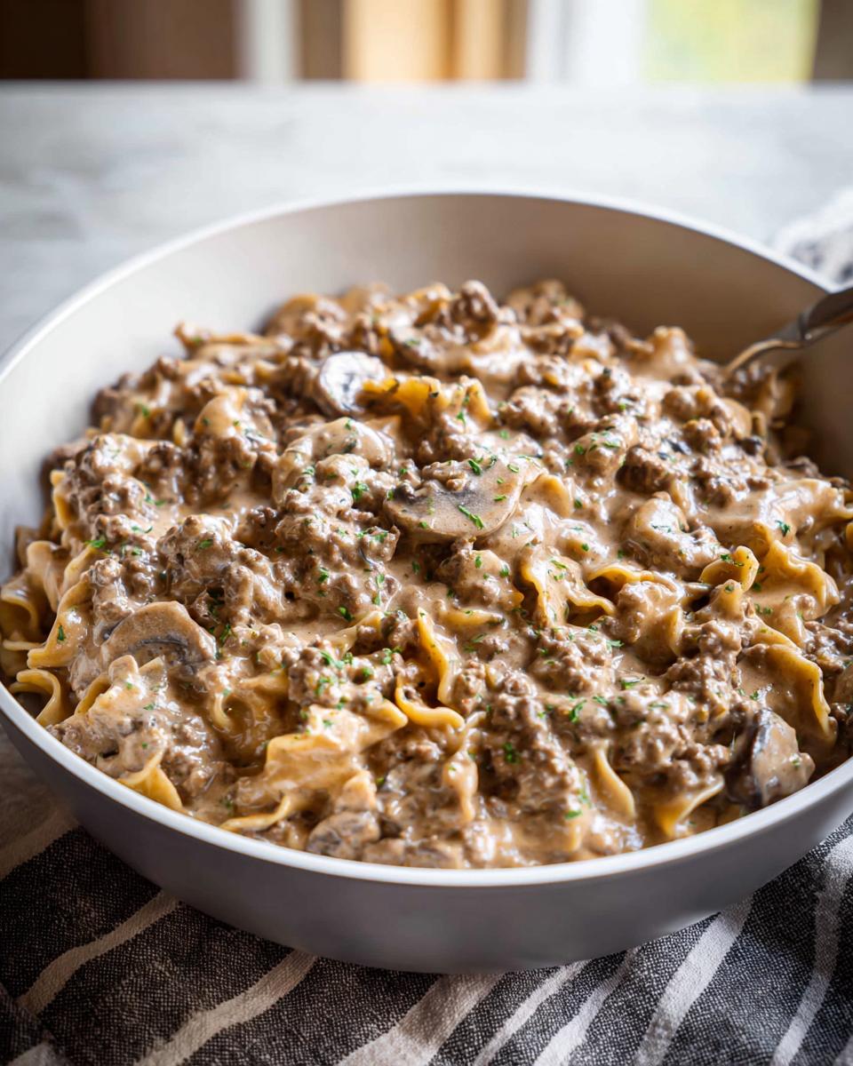 A close-up of creamy One Pot Ground Beef Stroganoff with egg noodles and mushrooms, garnished with parsley.