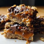 Close-up of stacked Salted Caramel Chocolate Chip Cookie Bars with gooey caramel and sea salt flakes.