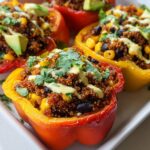 Close-up of vibrant Stuffed Bell Peppers with Quinoa and Black Beans, topped with avocado and cilantro.