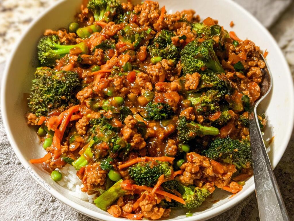 Close-up of a Teriyaki Ground Turkey Bowl served over white rice with broccoli florets and shredded carrots.