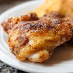 Close-up of a perfectly seasoned and crispy piece of air fryer chicken, ready in 25 minutes.