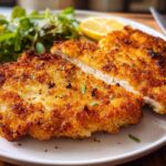 Close-up of a golden brown, crispy breaded chicken breast cooked in the air fryer, sliced open.
