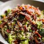 Close-up of a vibrant broccoli couscous salad topped with crispy bacon and Parmesan cheese, a great veggie sides recipe.