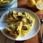 Two slices of a baked egg frittata with broccoli and red onion served on a white plate, part of 25 Genius Egg Recipes Ideas.
