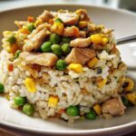 A molded serving of chicken and vegetable Rice Bowls Recipes, featuring white rice mixed with peas and corn.