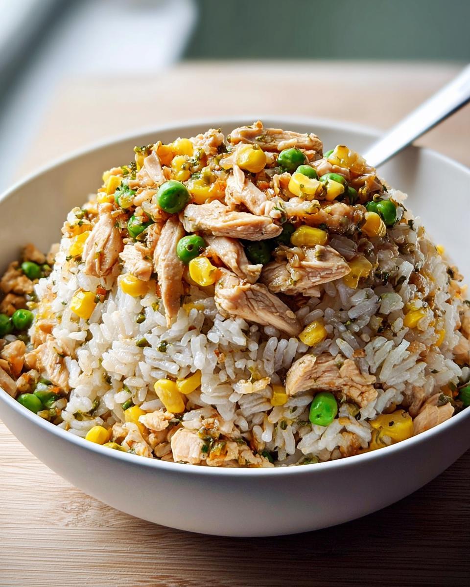 A close-up of a satisfying chicken and vegetable Rice Bowls Recipe topped with corn and peas over white rice.