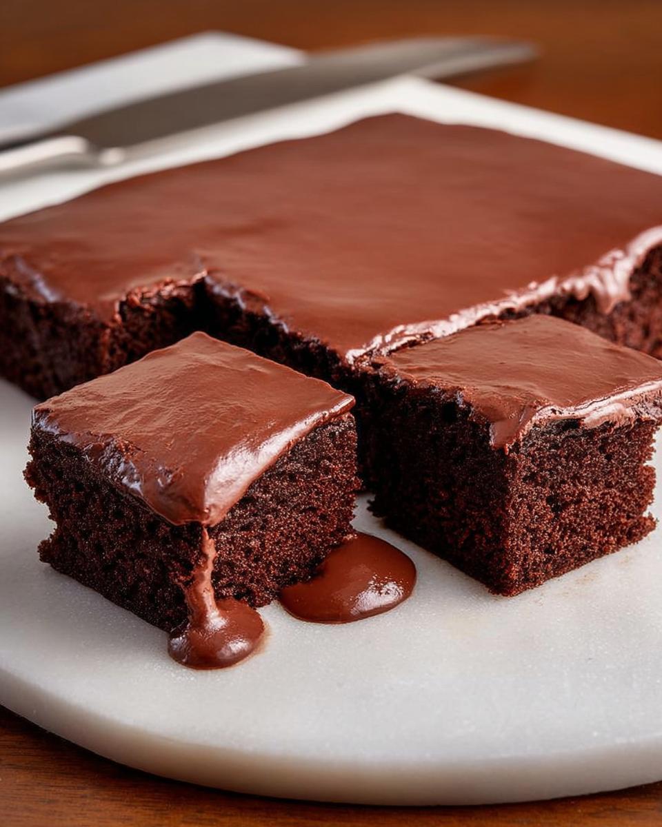 Close-up of rich, moist chocolate cake ideas recipes cut into squares with thick chocolate frosting.