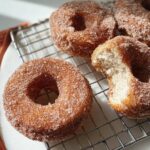 Close-up of freshly made cinnamon sugar donuts, one with a bite taken out, featured in breakfast ideas recipes.