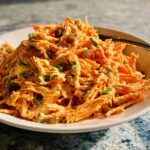A mound of shredded carrot salad with raisins and green onions, perfect for Veggie Sides Recipes in 15 Minutes.